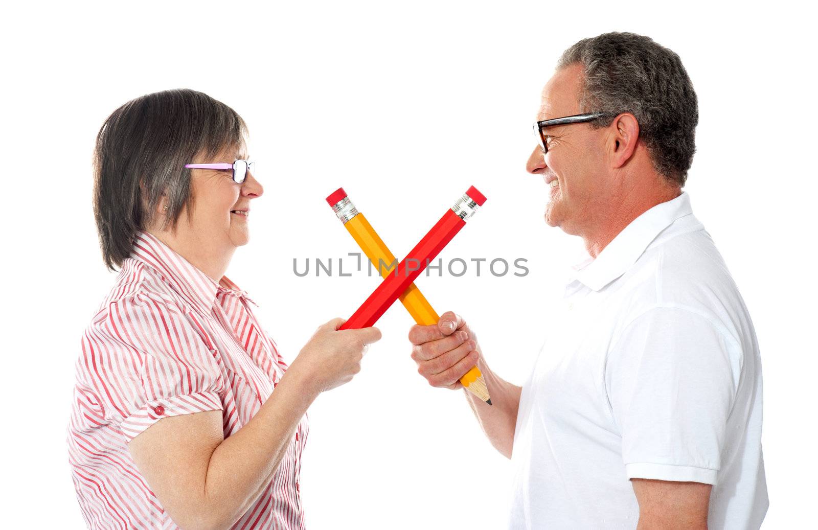 Smiling couple holding big pencils by stockyimages