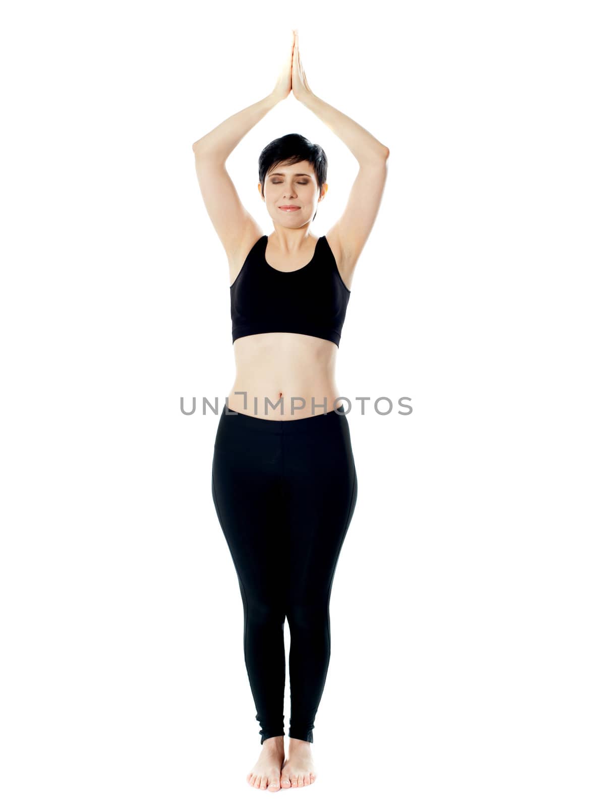 Full-length view of fit woman doing yoga. Standing with hands held together over the head