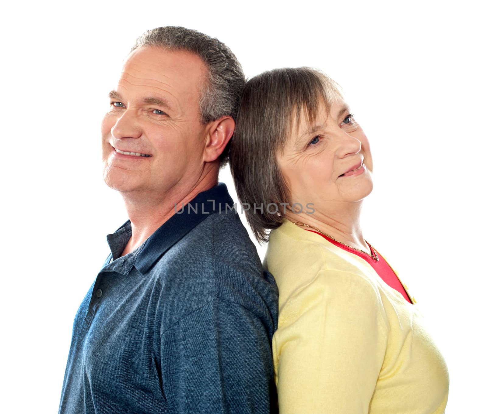 Aged couple smiling and posing back to back in front of camera
