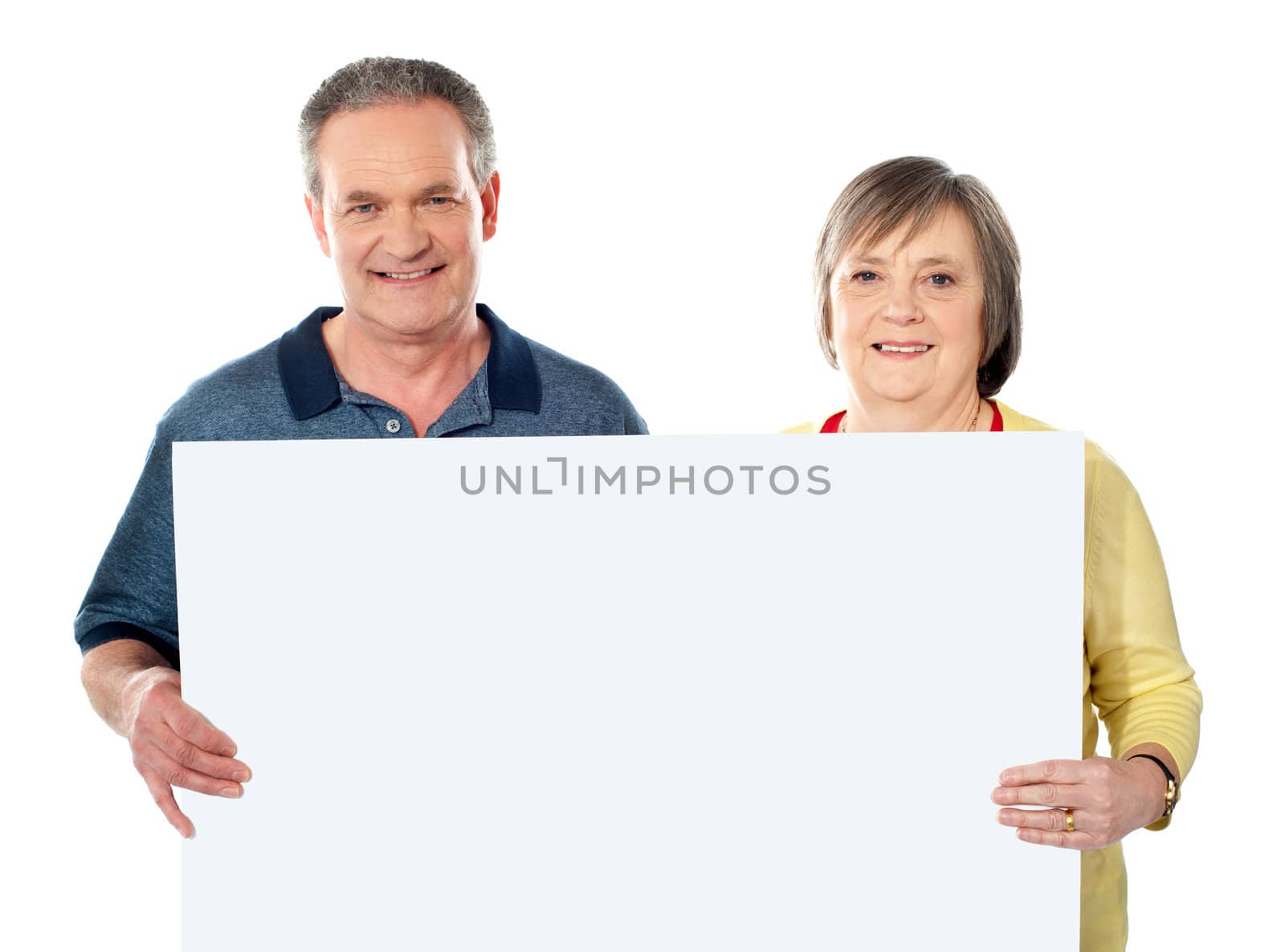Smiling aged couple holding blank white poster showing it to camera
