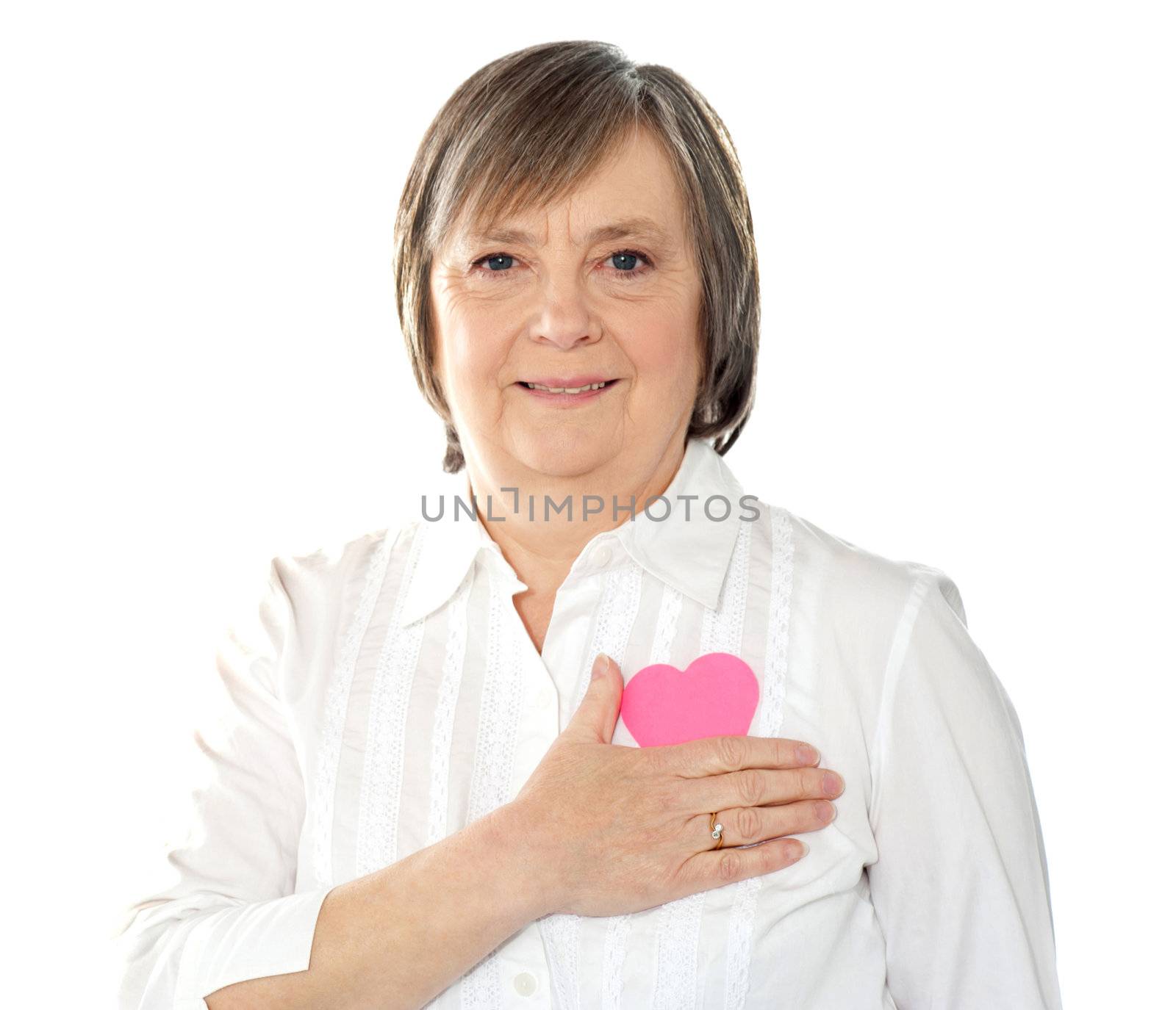 Mature woman holding her paper heart close to body. Dressed in casuals