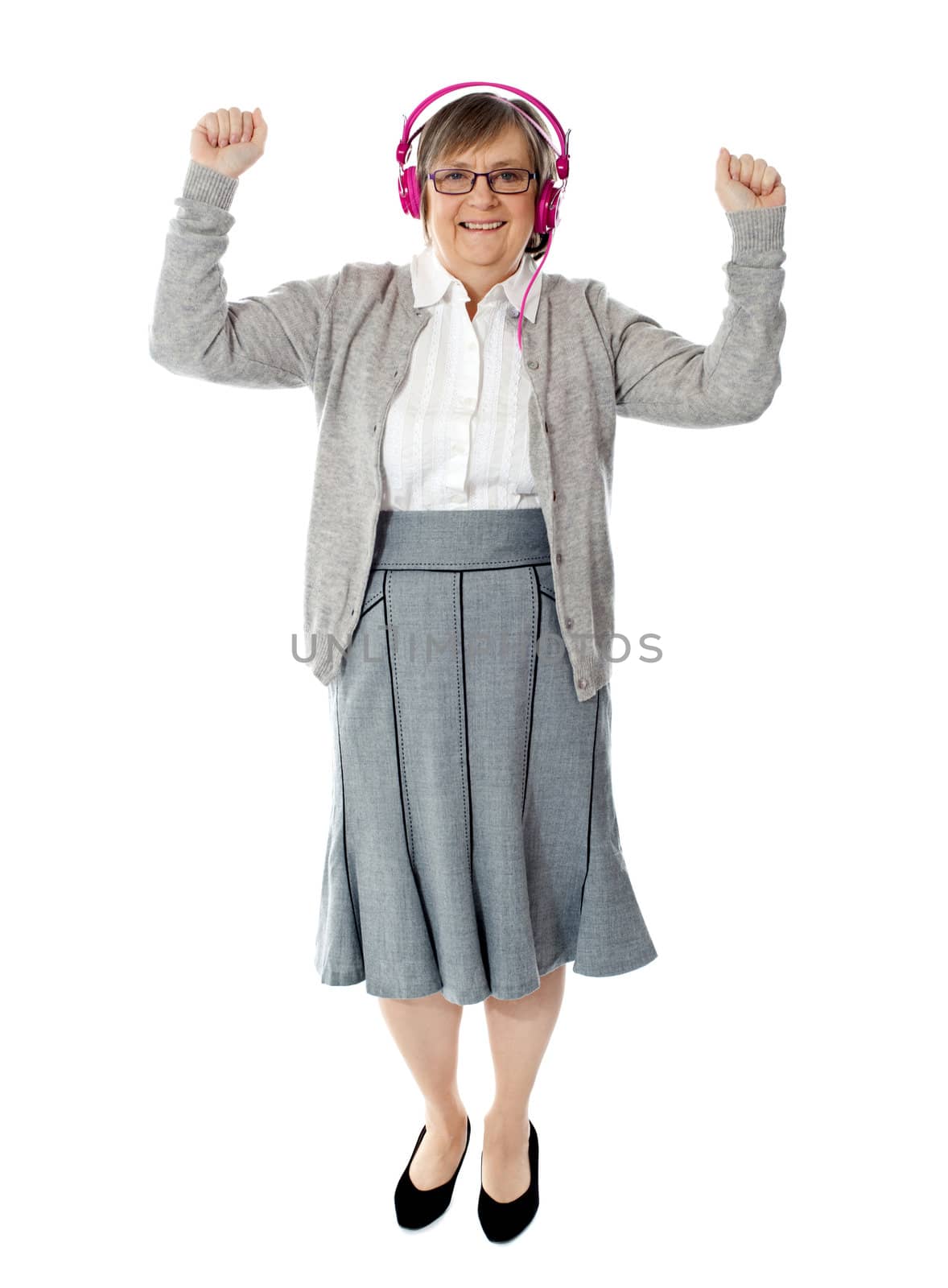 Cheerful aged woman enjoying music. Dancing with arms up