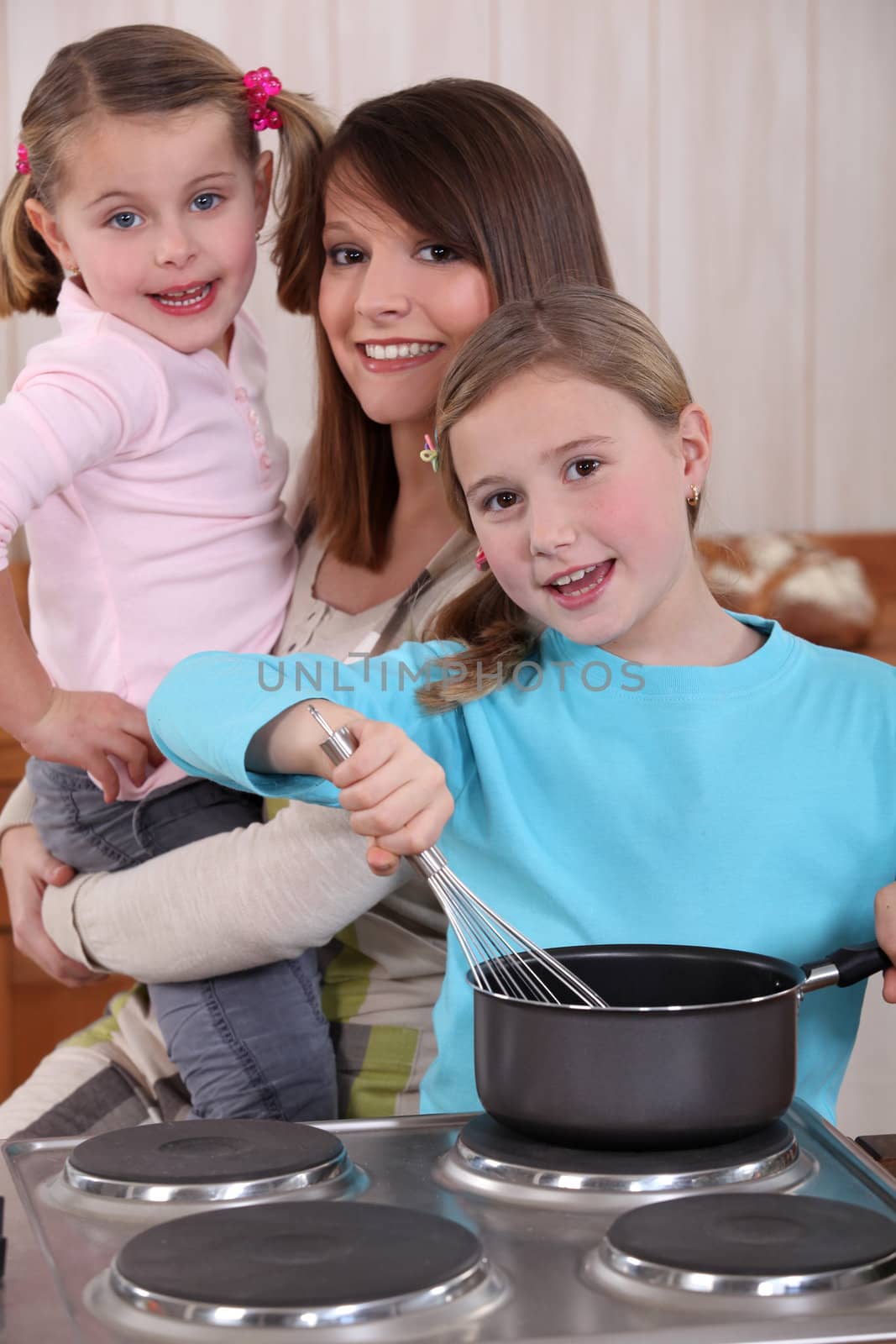 Mother and two young daughters cooking by phovoir