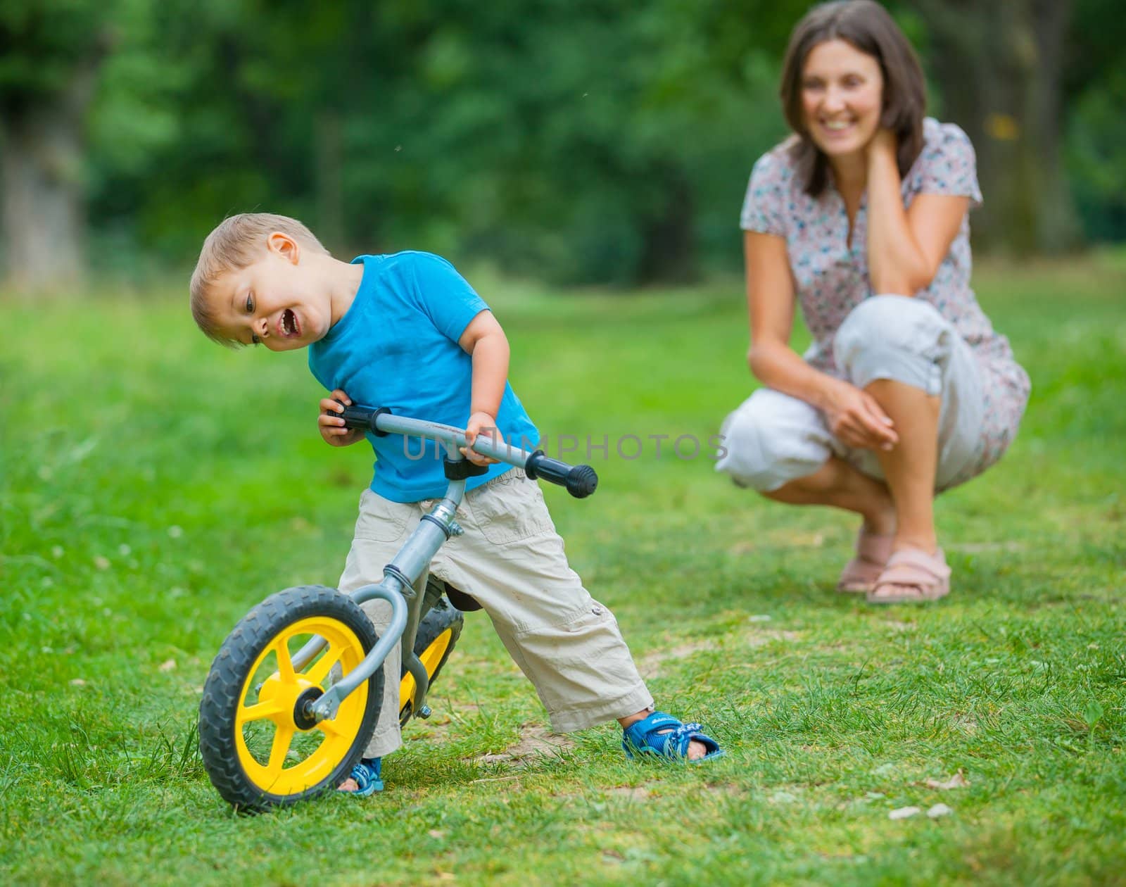 Portrait of little boy on a bicycle and his mother in the summer park