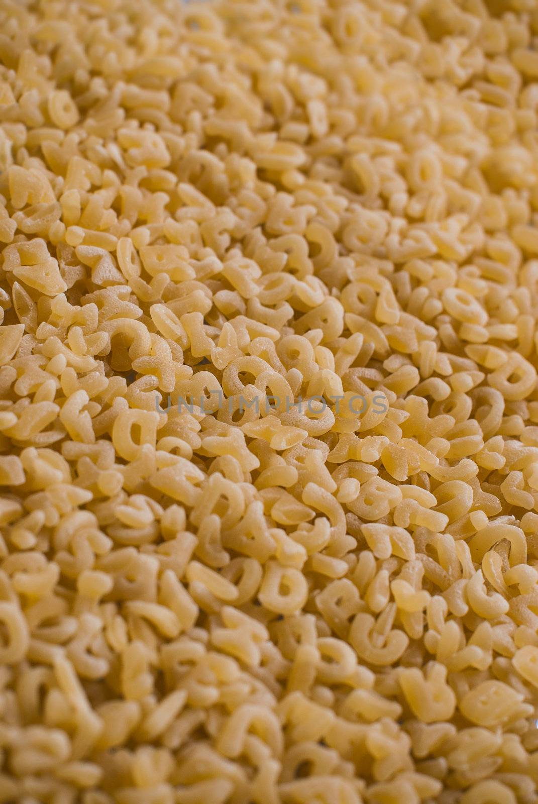 Close-up background of alphabet noodle showing letters.