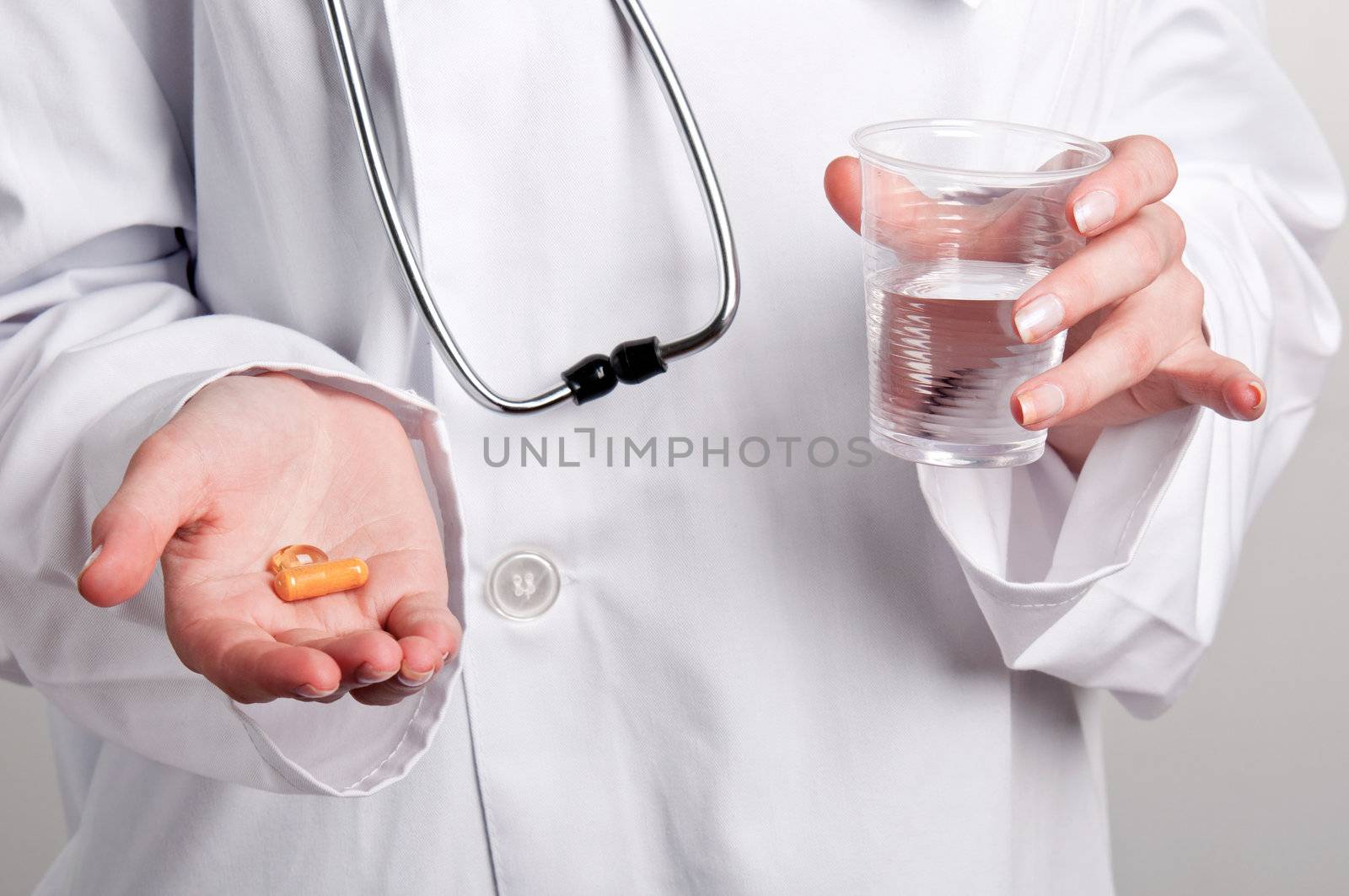 Female doctor holds pills on one hand and a glass of water on the other hand
