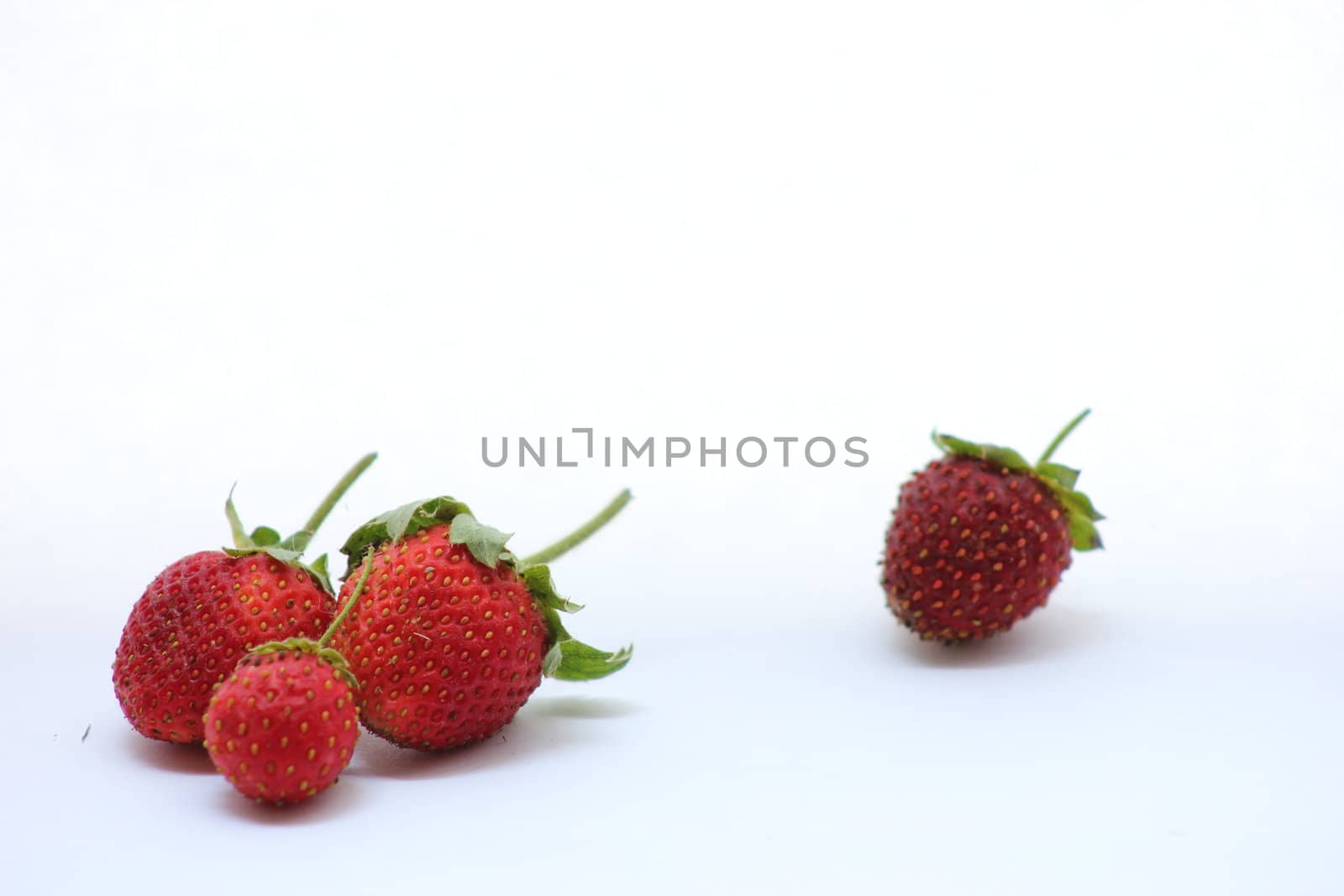 Strawberries grouped together with one left behind.