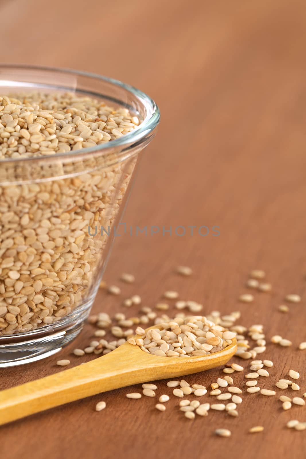 Sesame seeds on small wooden spoon with a glass bowl beside (Selective Focus, Focus on the front sesame seeds on the spoon)