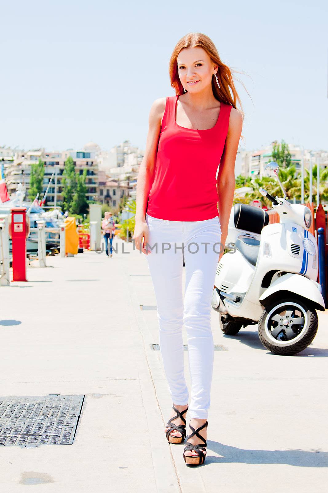 Photo of a young and beautiful girl walking down the street along the marina