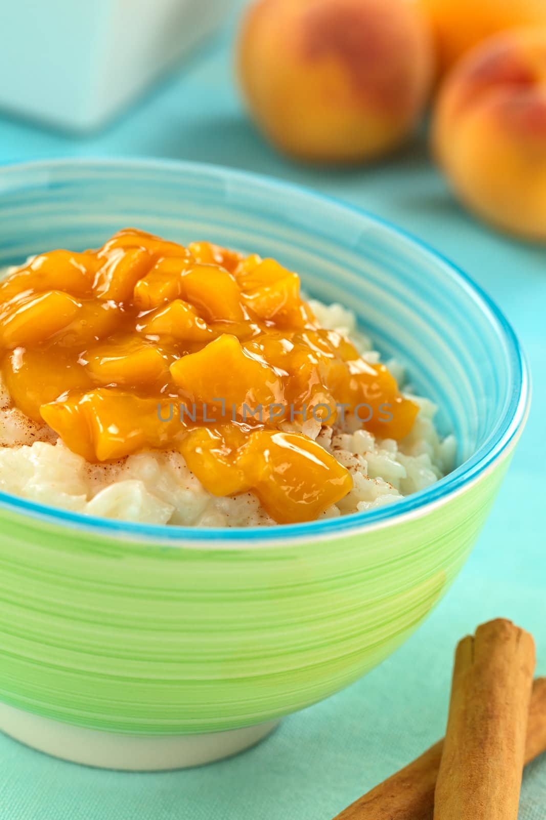 Colorful bowl full of fresh homemade rice pudding with peach compote (Selective Focus, Focus one third into the peach compote)