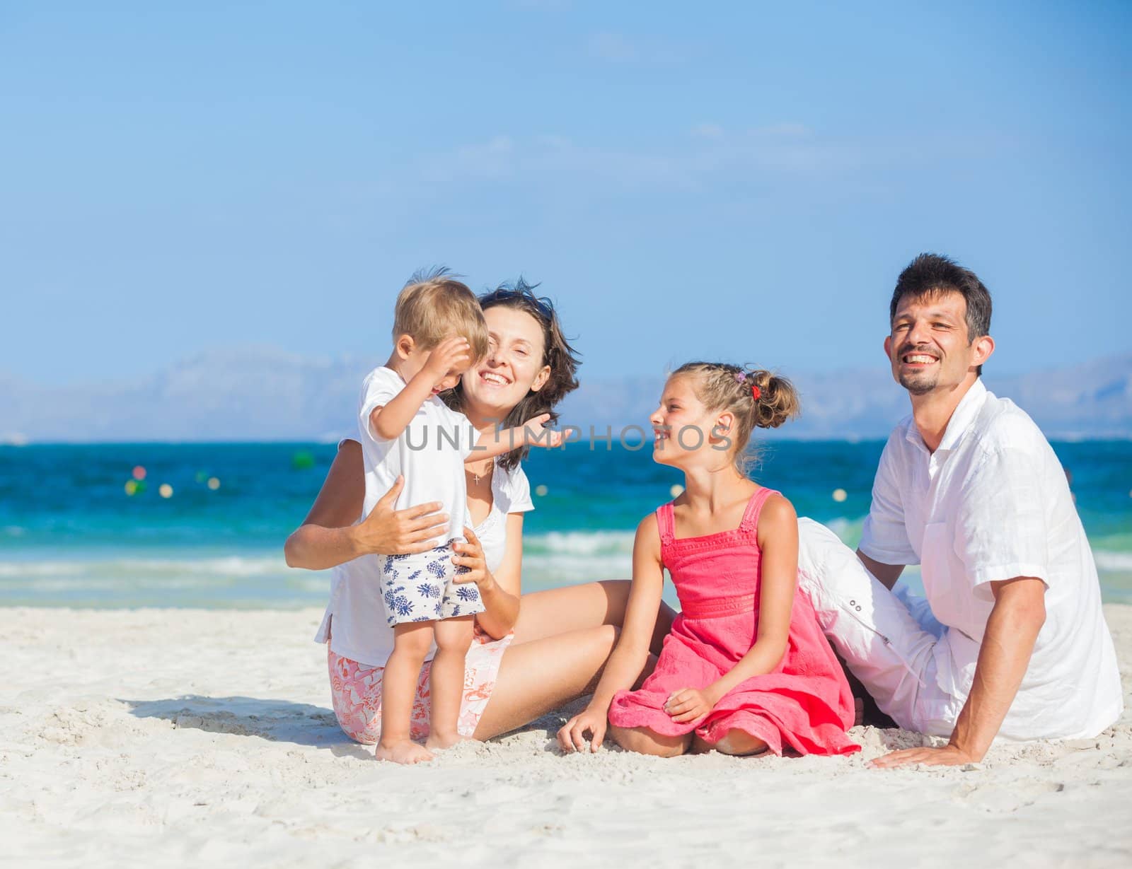 Family of four on tropical beach by maxoliki