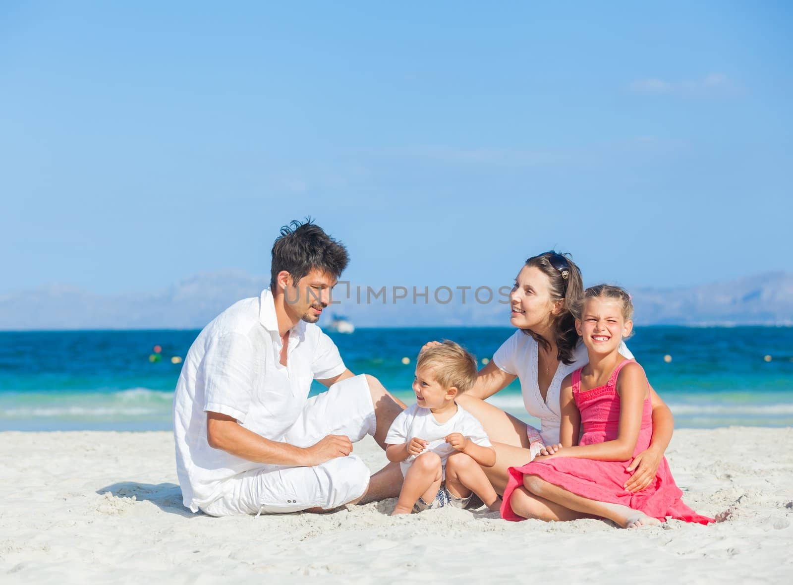 Family of four on tropical beach by maxoliki