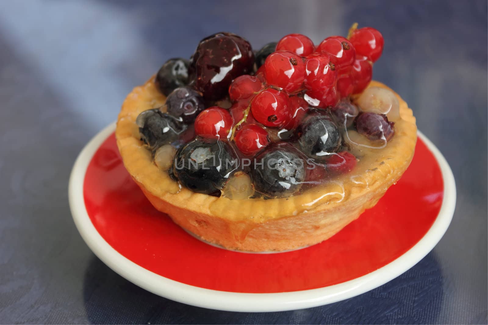 Close up shot of tartlet with various berries and red currants on top