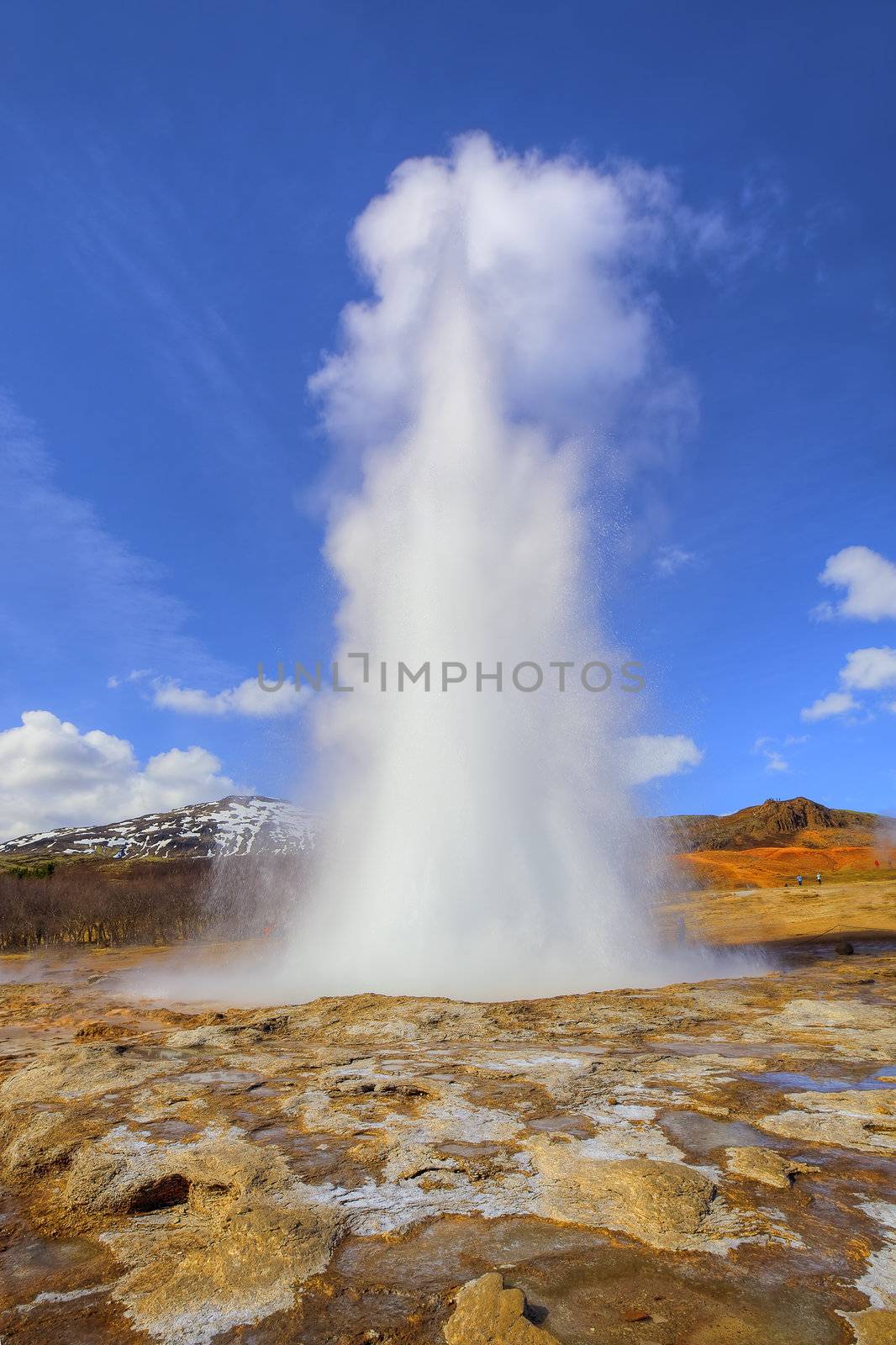 Icelandic Geyser erupts, with blue sky in the background