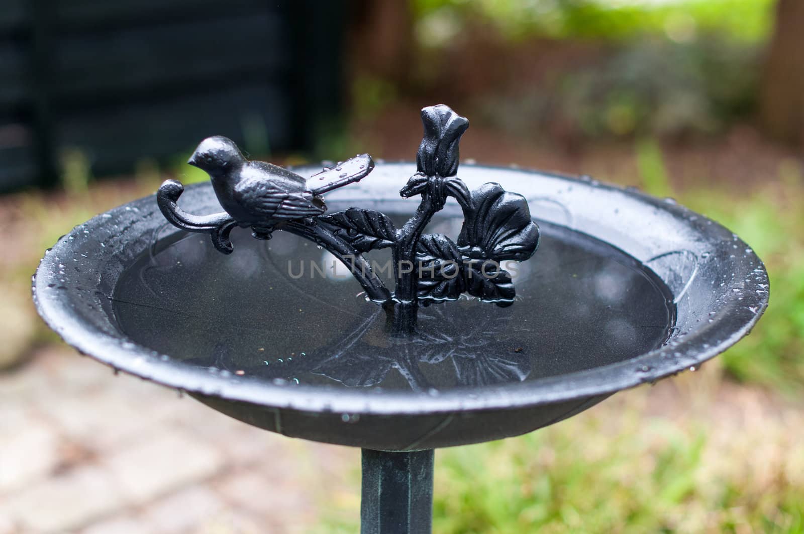 A richly decorated metal birdbath in a garden