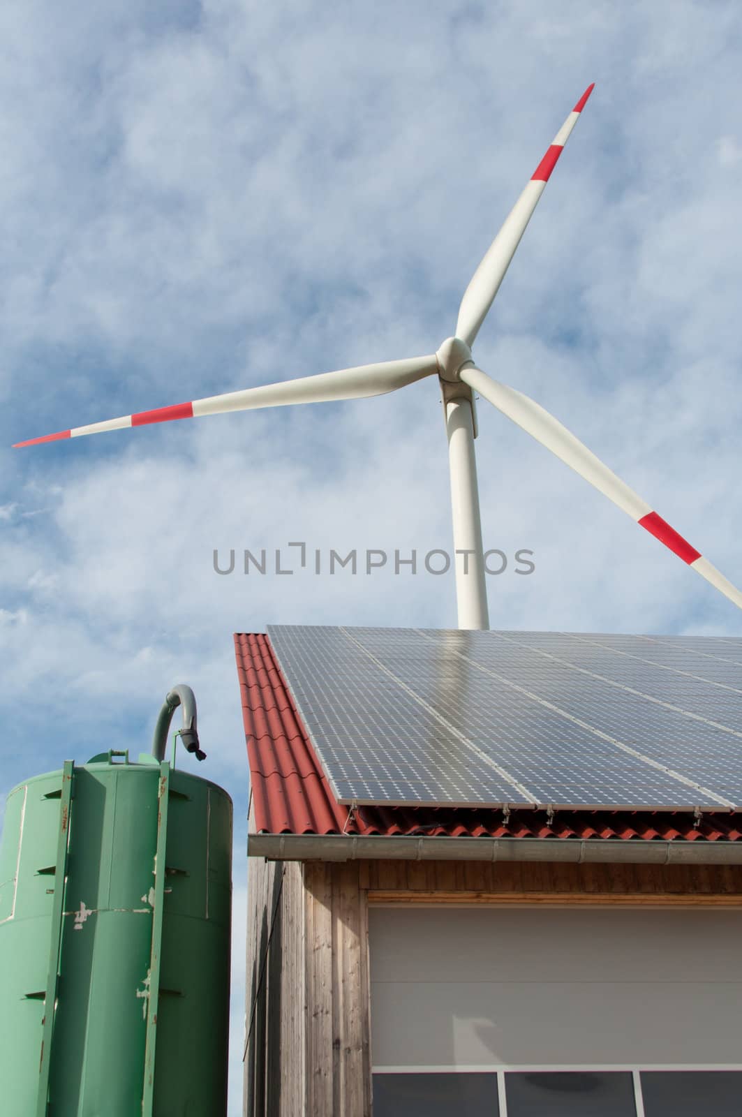 barn covered with solar panels and wind turbine in the background