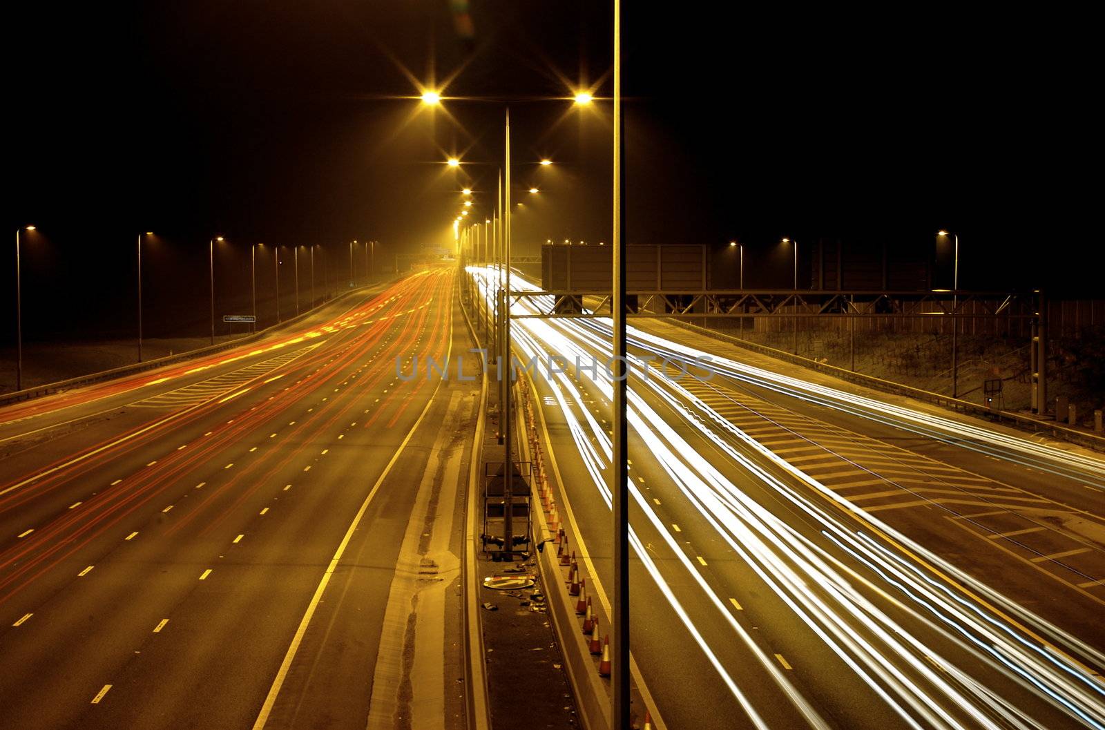 Long exposure image of fast moving traffic at night - where the car lights are glowing lines white and red and everything else is clear.