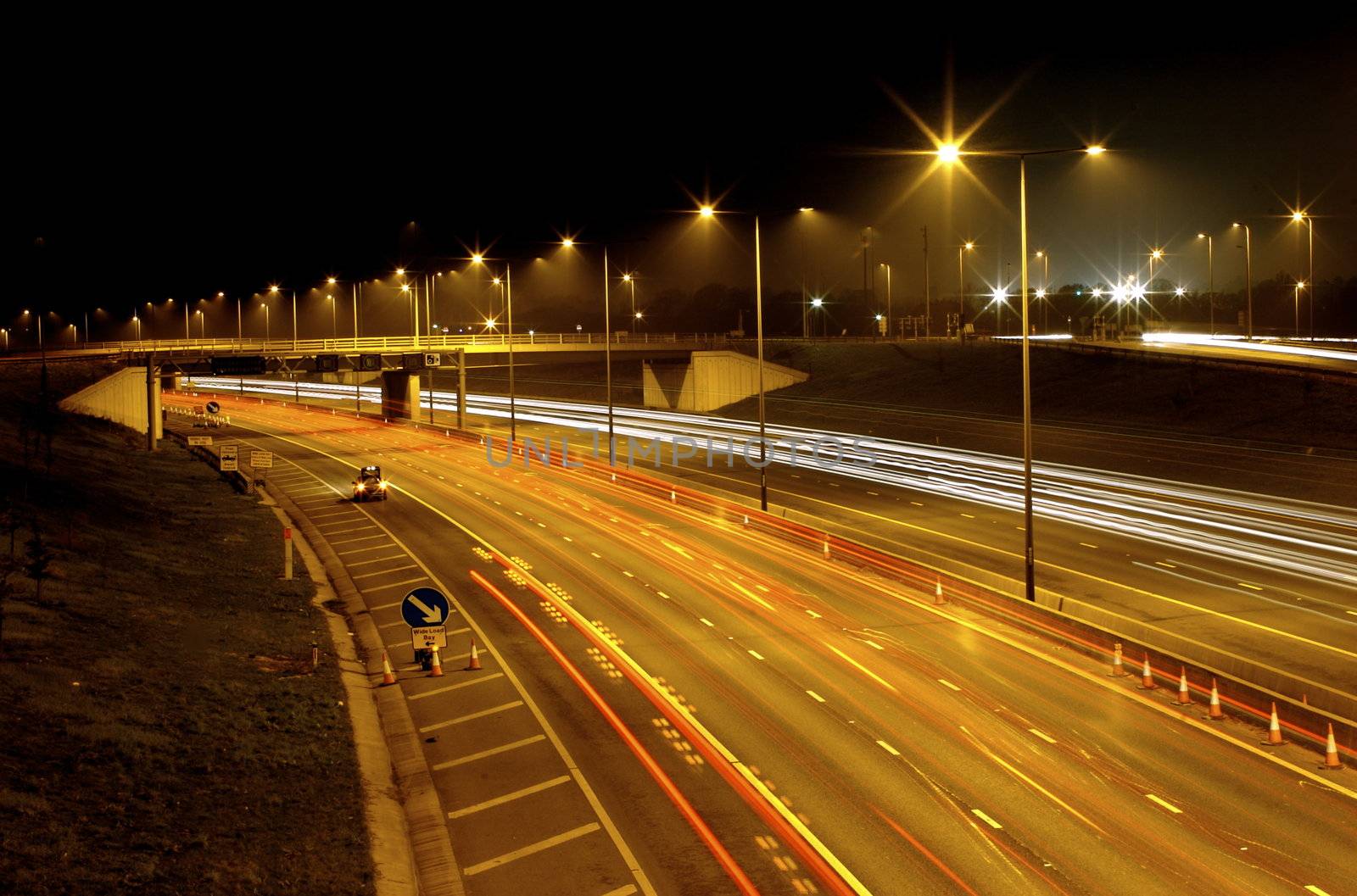 Long exposure image of fast moving traffic at night - where the car lights are glowing lines white and red and everything else is clear.