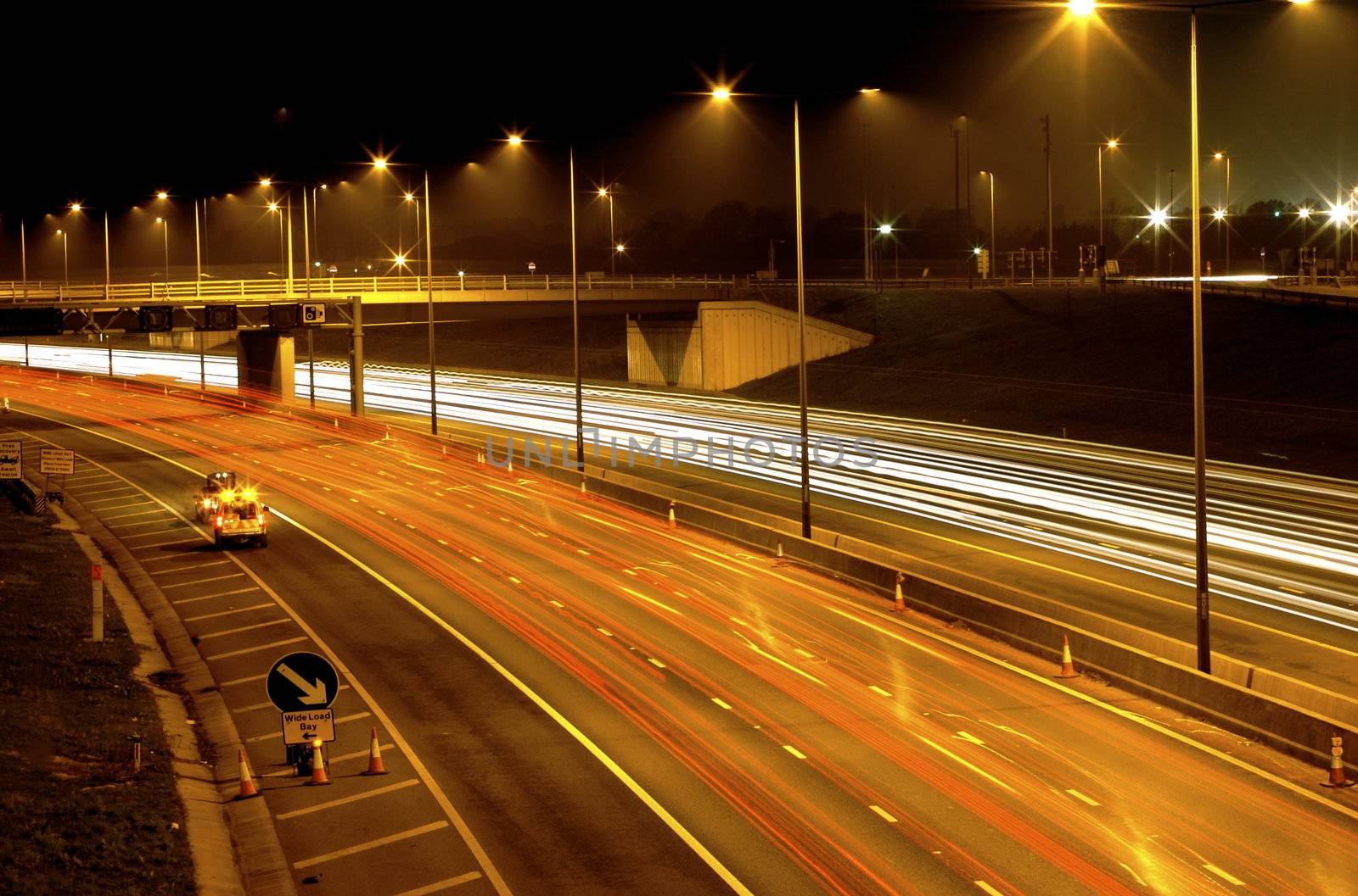 Long exposure image of fast moving traffic at night - where the car lights are glowing lines white and red and everything else is clear.