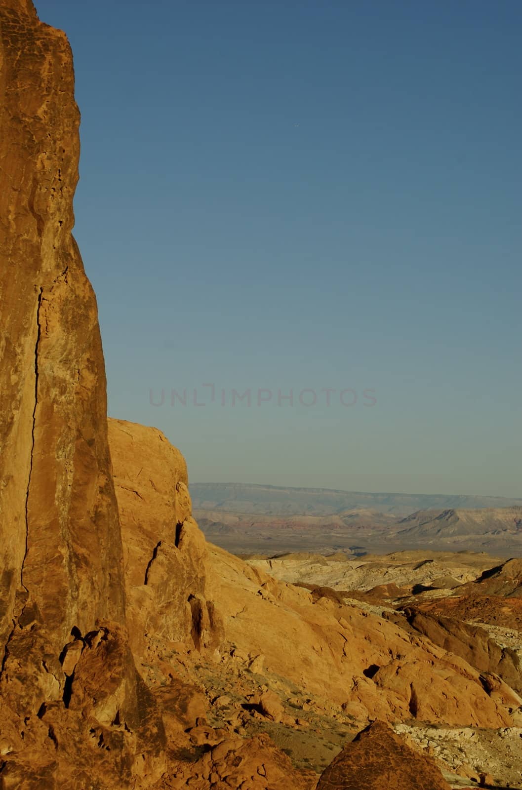 View across Valley Of Fire framed with red rock across the desert with the horizon and bright blue sky on the distance with copy space.