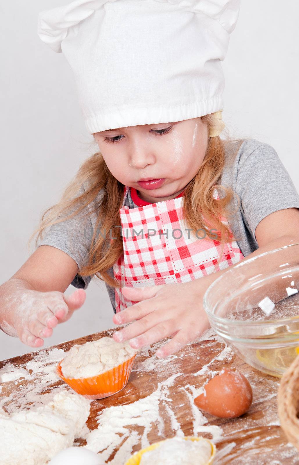 girl in chef's hat cooking dough for cake