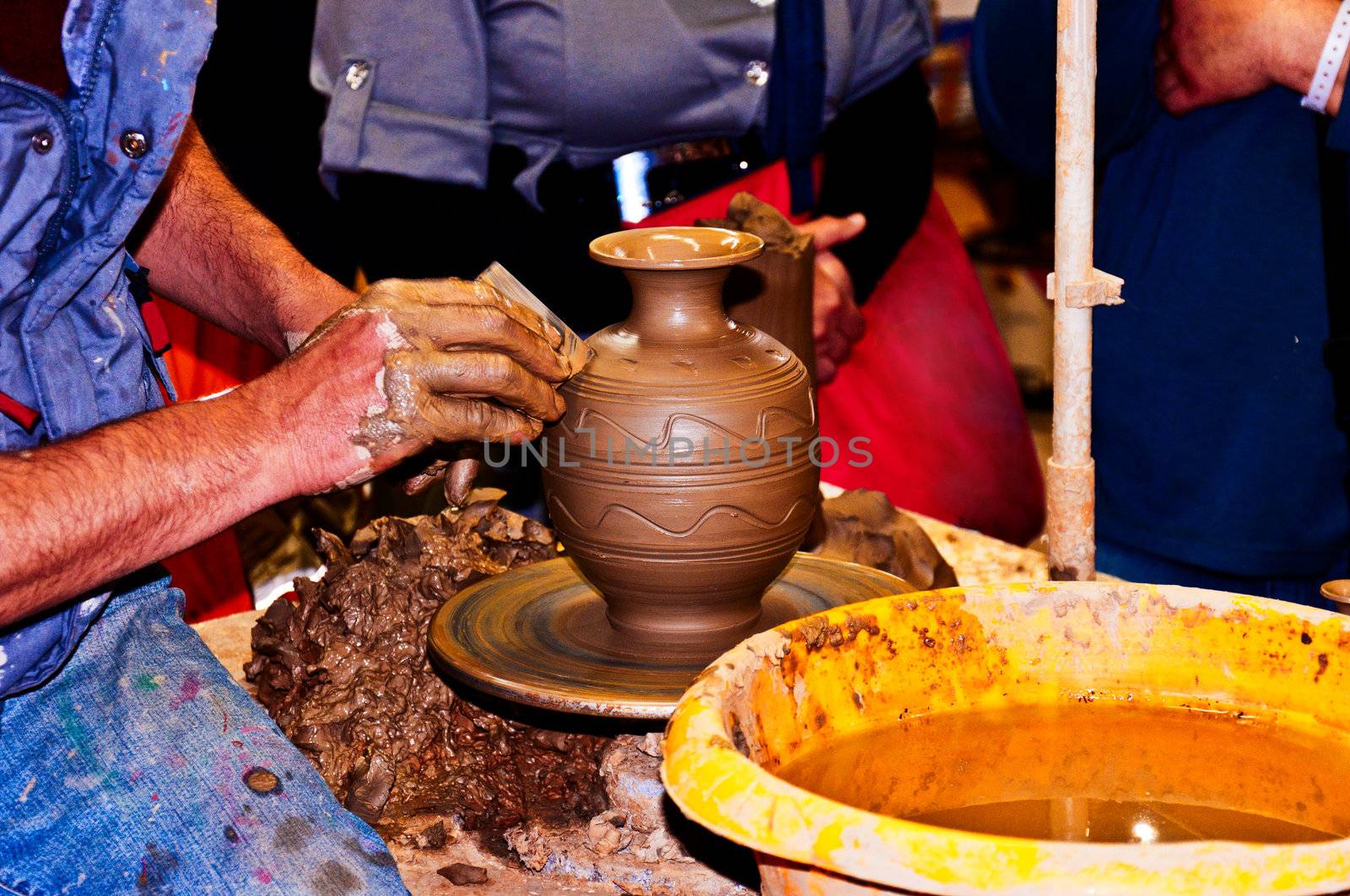 Hands of a potter, creating  ornament on jar