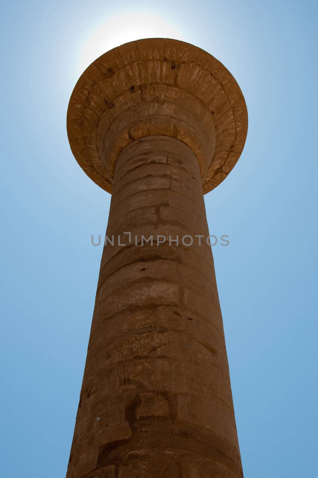 Stone ancient column with sun behind in Karnak Temple by Nanisimova