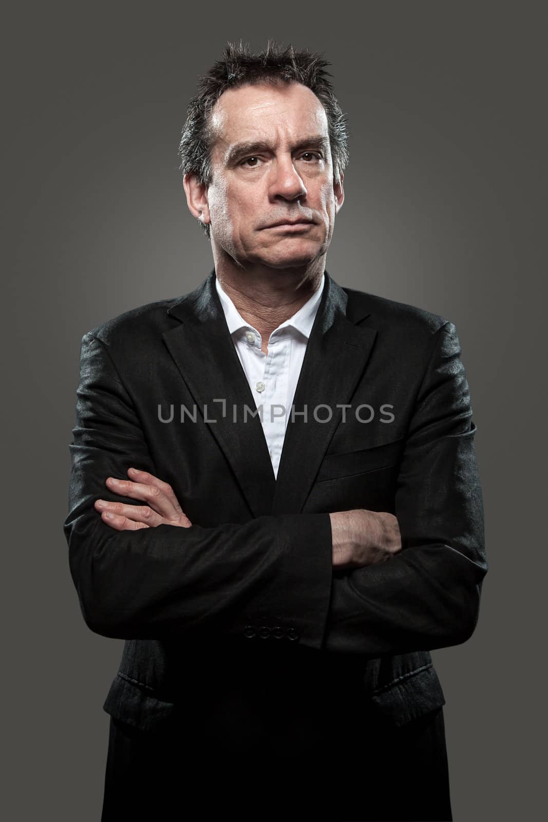 Grumpy Stern Middle Age Business Man in Suit Arms Folded Grey Background High Contrast Grunge Look