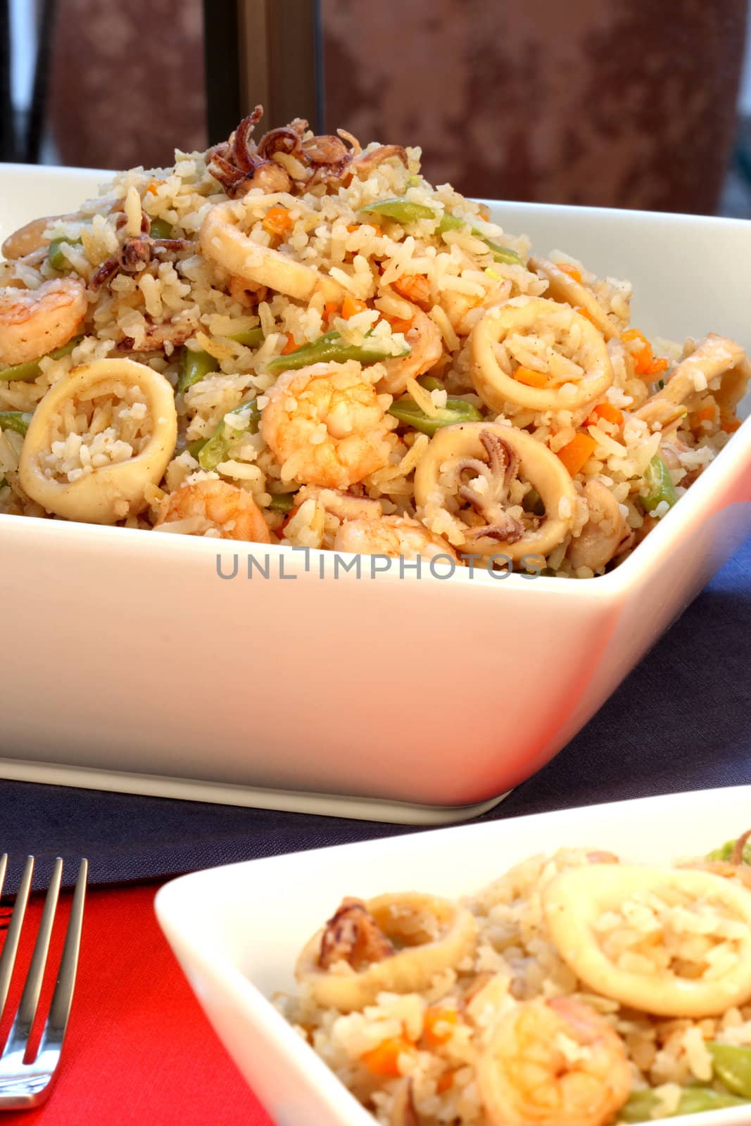 delicious calamary rice with assorted seafood and vegetables served on nice fancy table  