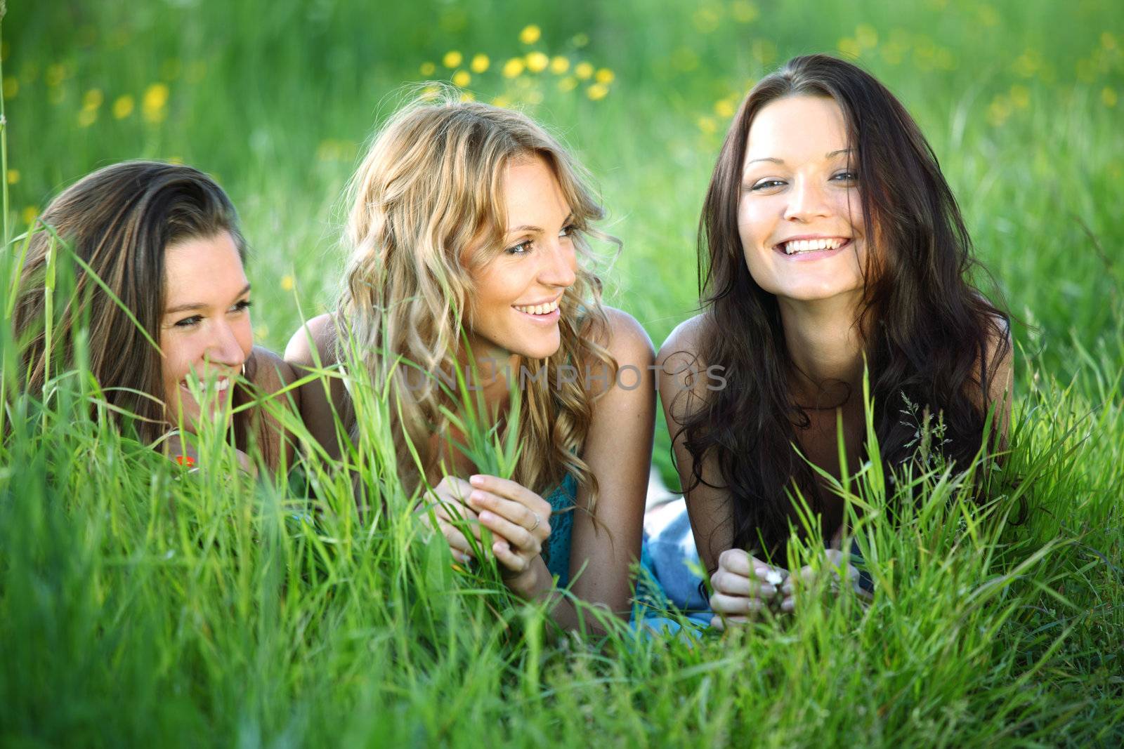 girlfriends lays on green grass and smile