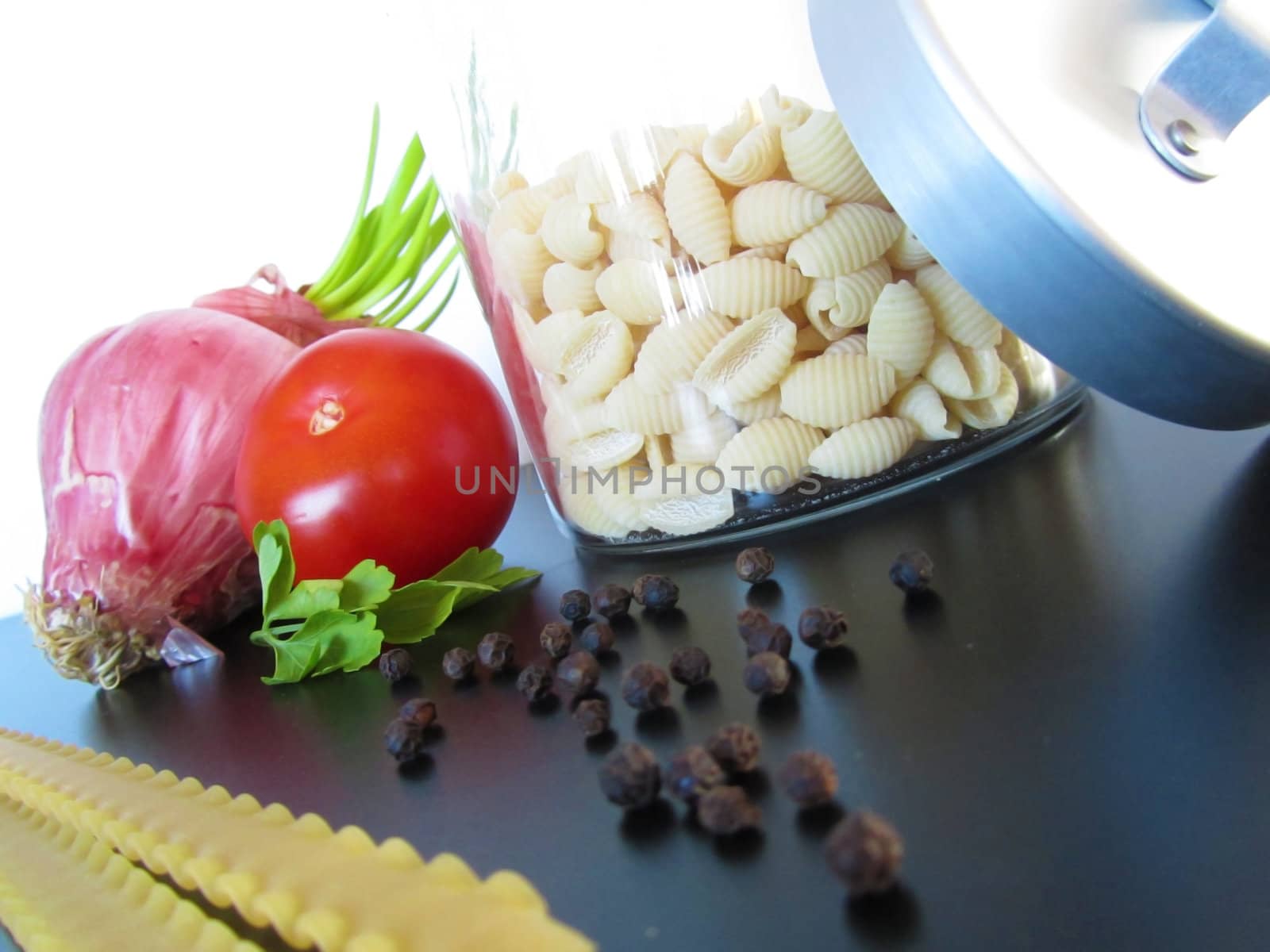 Mediterranean Ingredients:tomato, onion,parsley,pepper and pasta on a black table