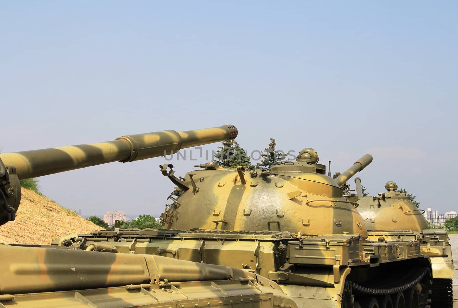 Moving tanks column against city trees and background