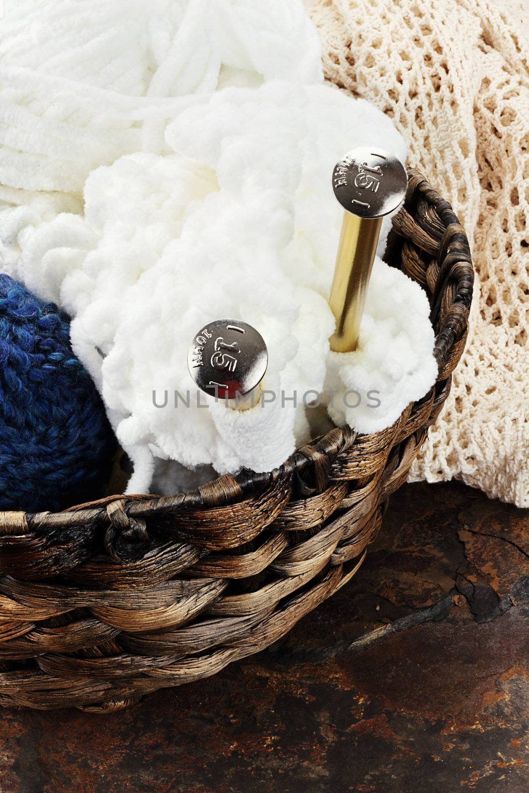 Basket of yarn with knitting needles on a rustic background. 
