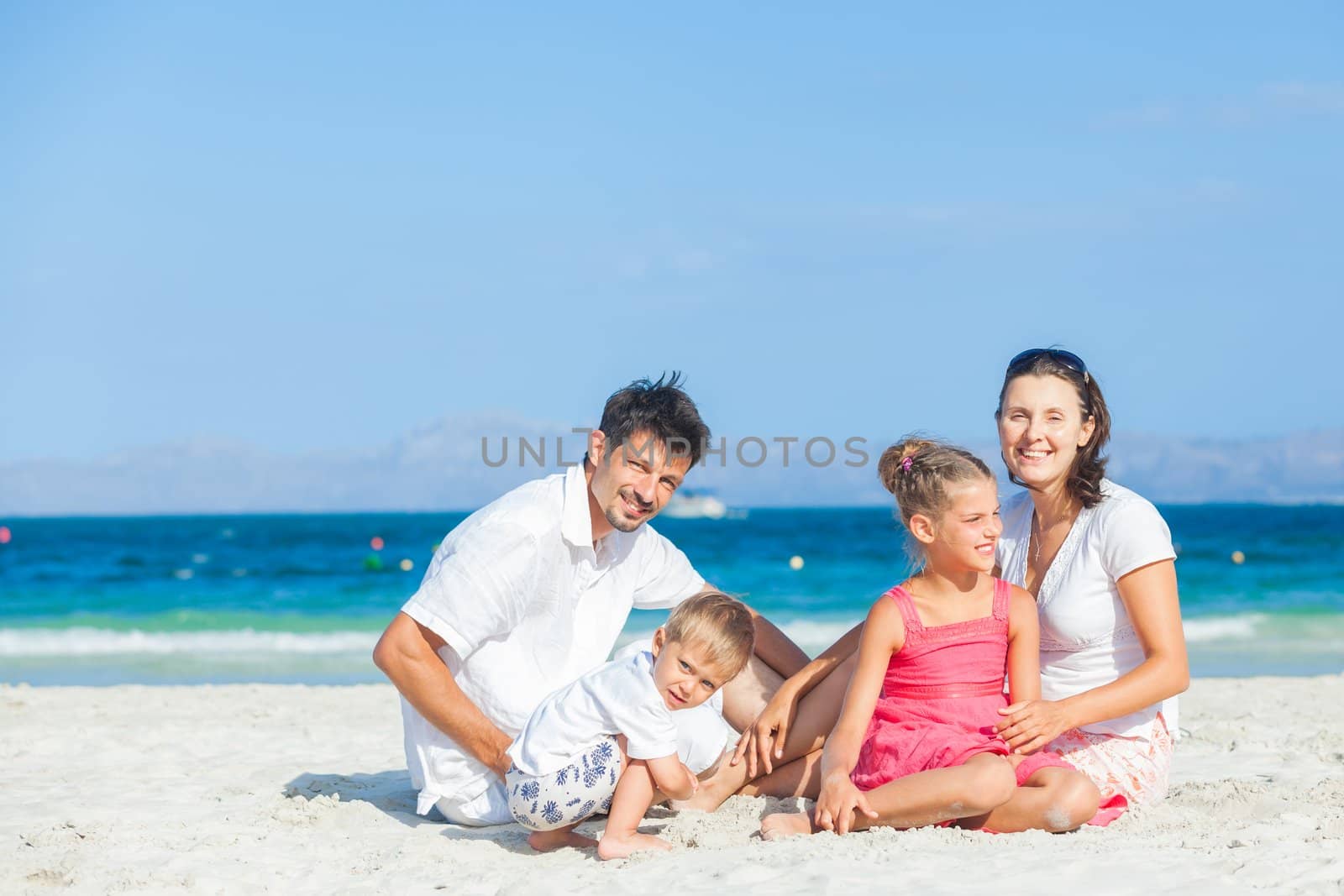 Family of four on tropical beach by maxoliki