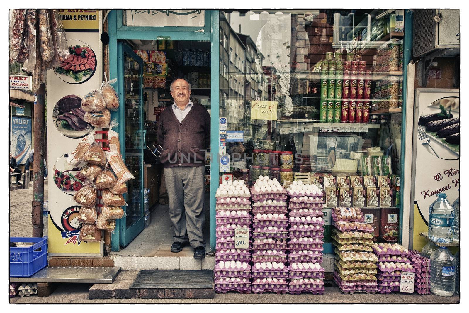 HAPPY TURKISH GROCER, ISTANBUL, TURKEY, APRIL 17, 2012: Proud and smiling grocer asking the photograper for being captured in the doorway of his shop.