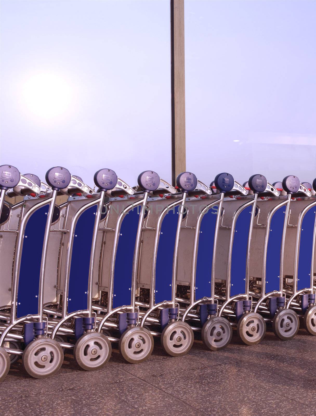 Row of luggage carts at busy airport, with selective focus on the closer carts