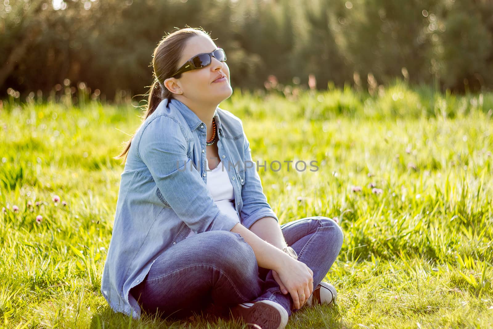 Smiling woman sunbathing sitting in a field by doble.d