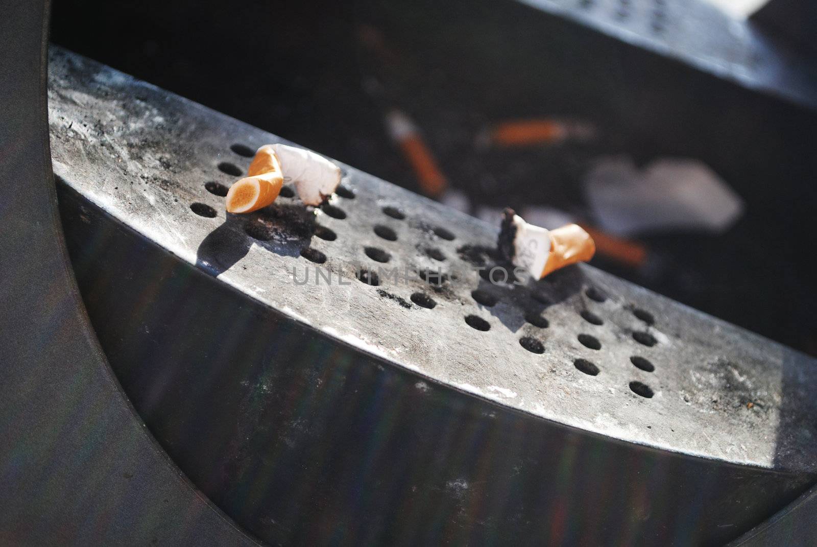 Cigarette stubs in an outdoors ashtray.