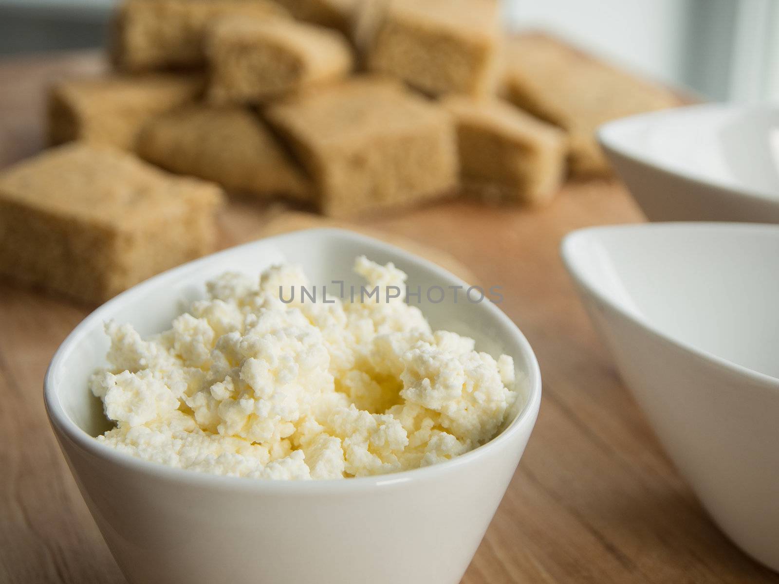 Homemade cottage cheese in a bowl on a cutting board