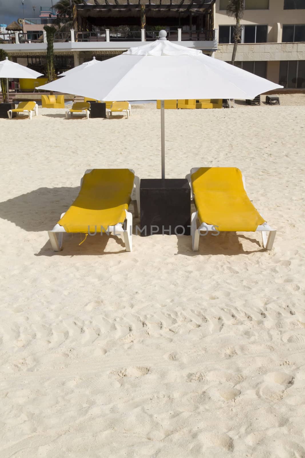 A pair of beach lounge chairs with umbrella