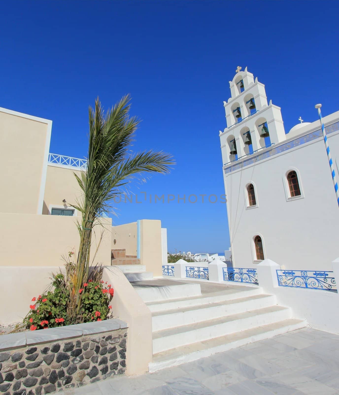 Belfry of traditional old style white Church of Panagia of Platsani on Caldera Square in village Oia of Cyclades Island Santorini Greece on the blue sky background