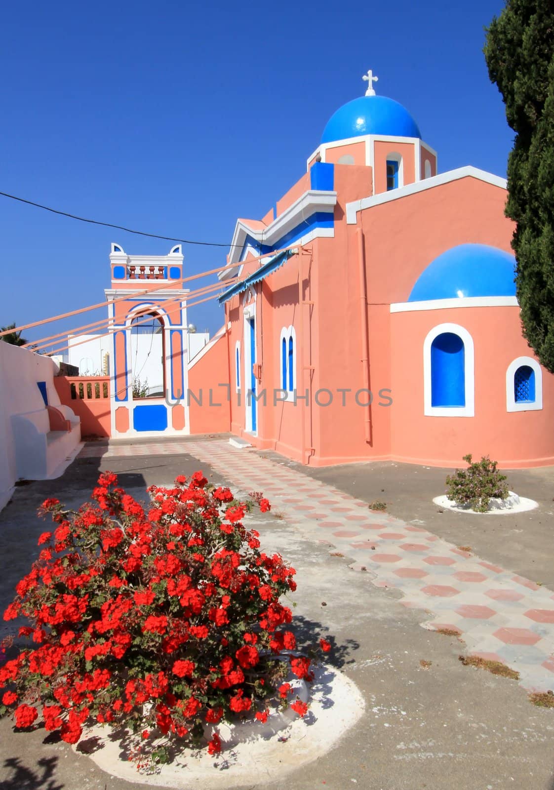 Colorful orthodox church with typical architecture and blue dome in Oia, Santorini island, Greece