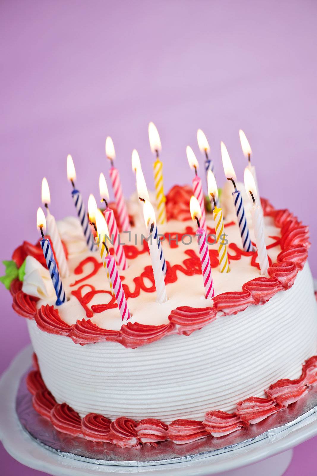 Birthday cake with burning candles on a plate on pink background