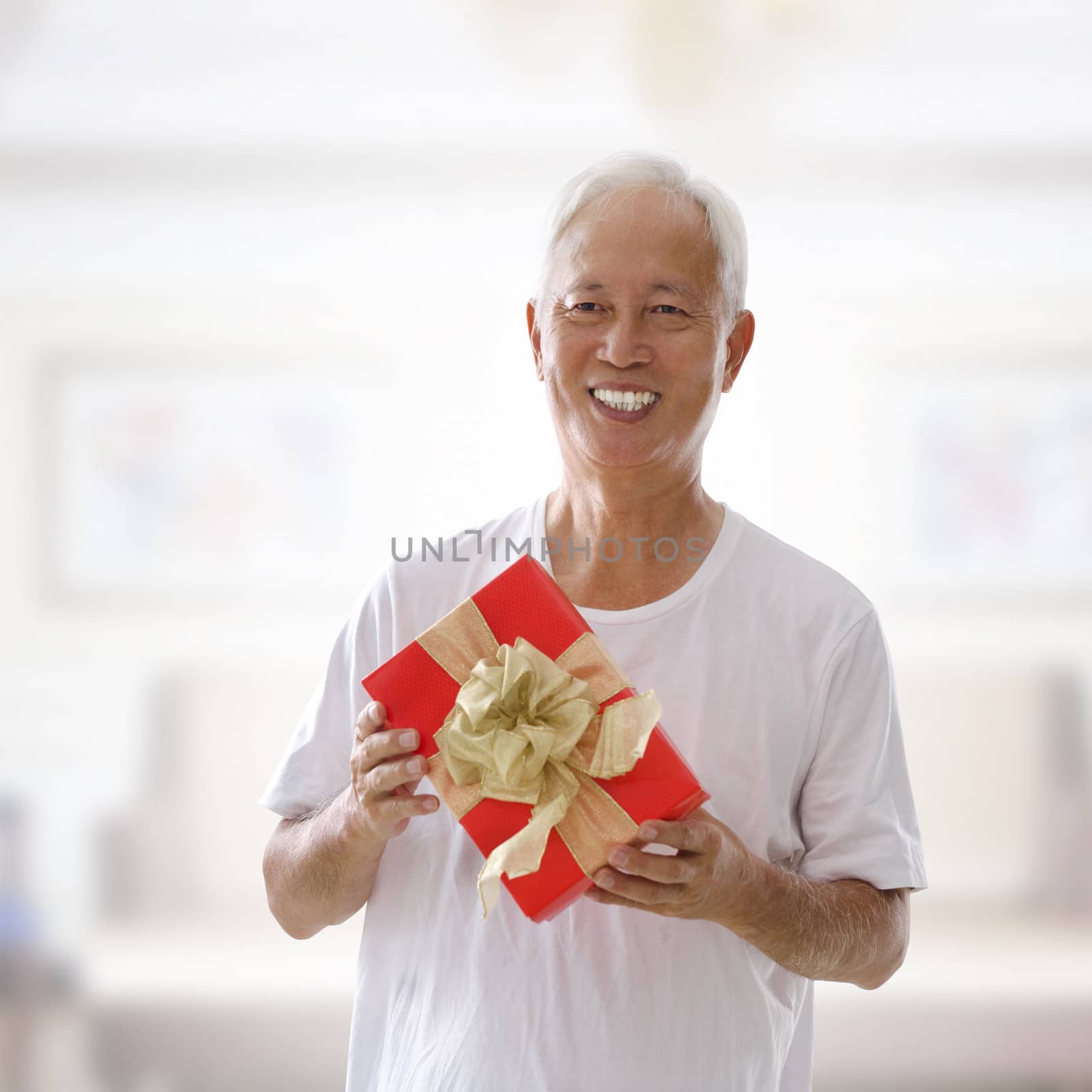Happy mixed race Senior Asian man holding a gift box and smiling