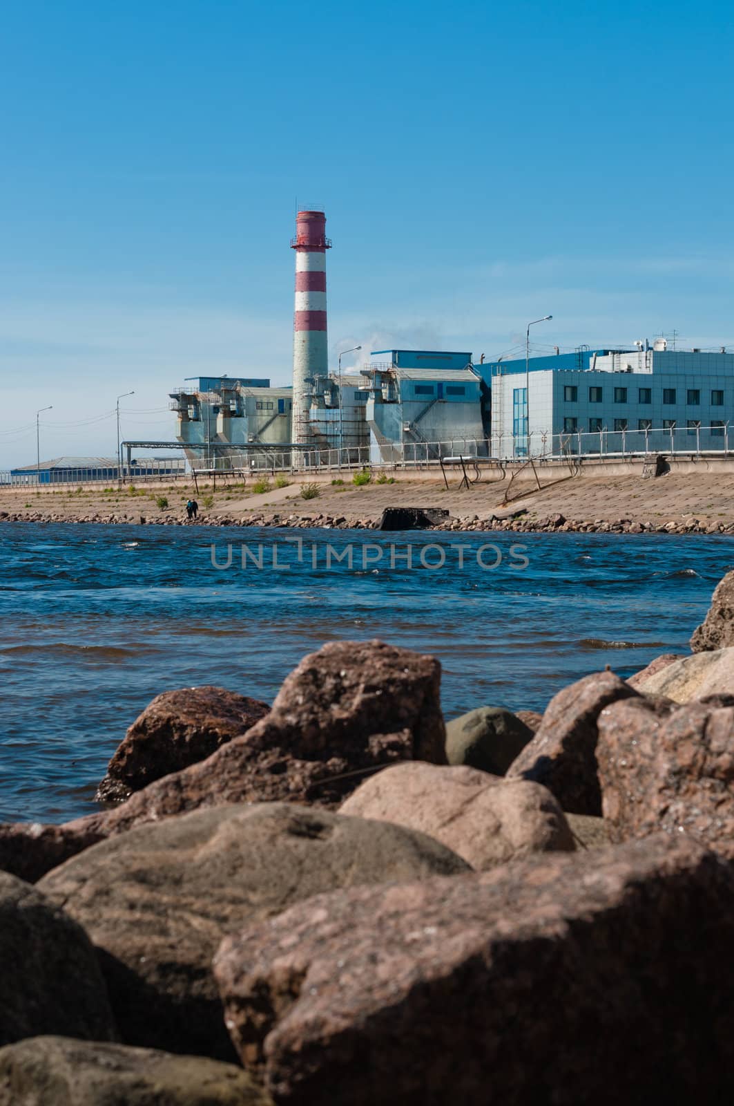 Modern factory, placed on embankment, with stones in front