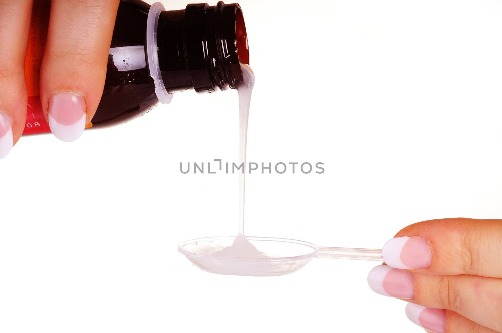 Liquid medicine pouring by female hands from bottle to measuring spoon. On white background.