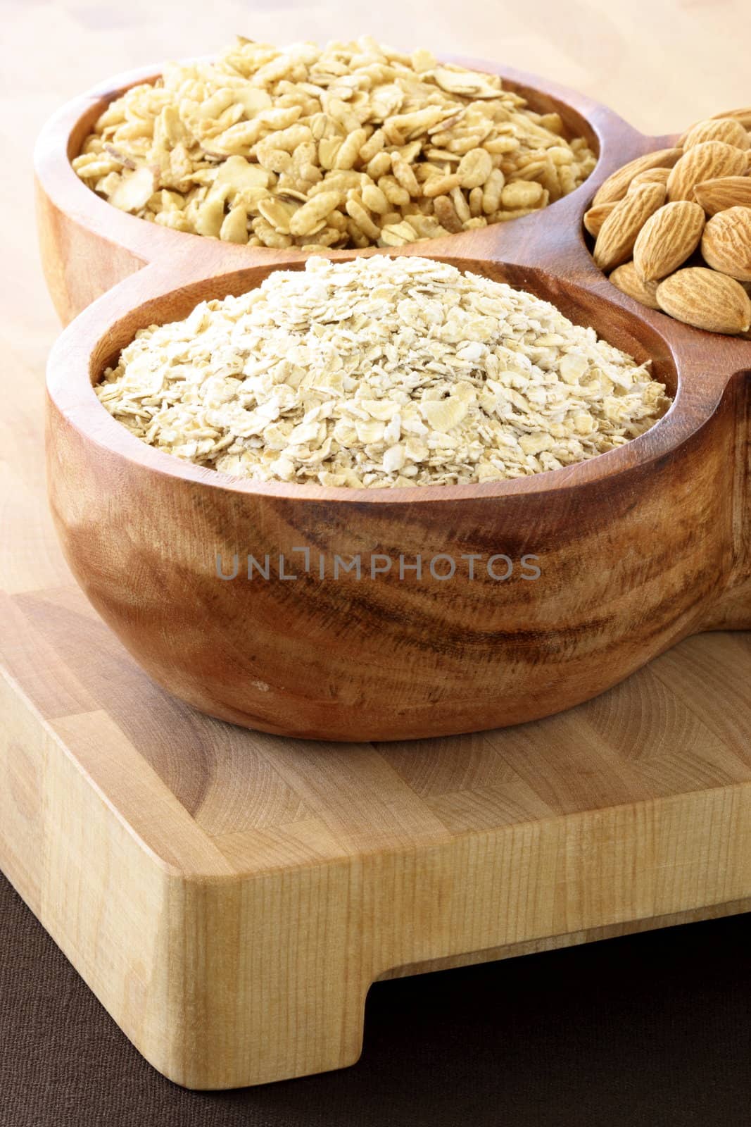 fresh healthy rolled oats, muesli and almonds on wooden rustic serving utensil. part of a healthy and delicious breakfast