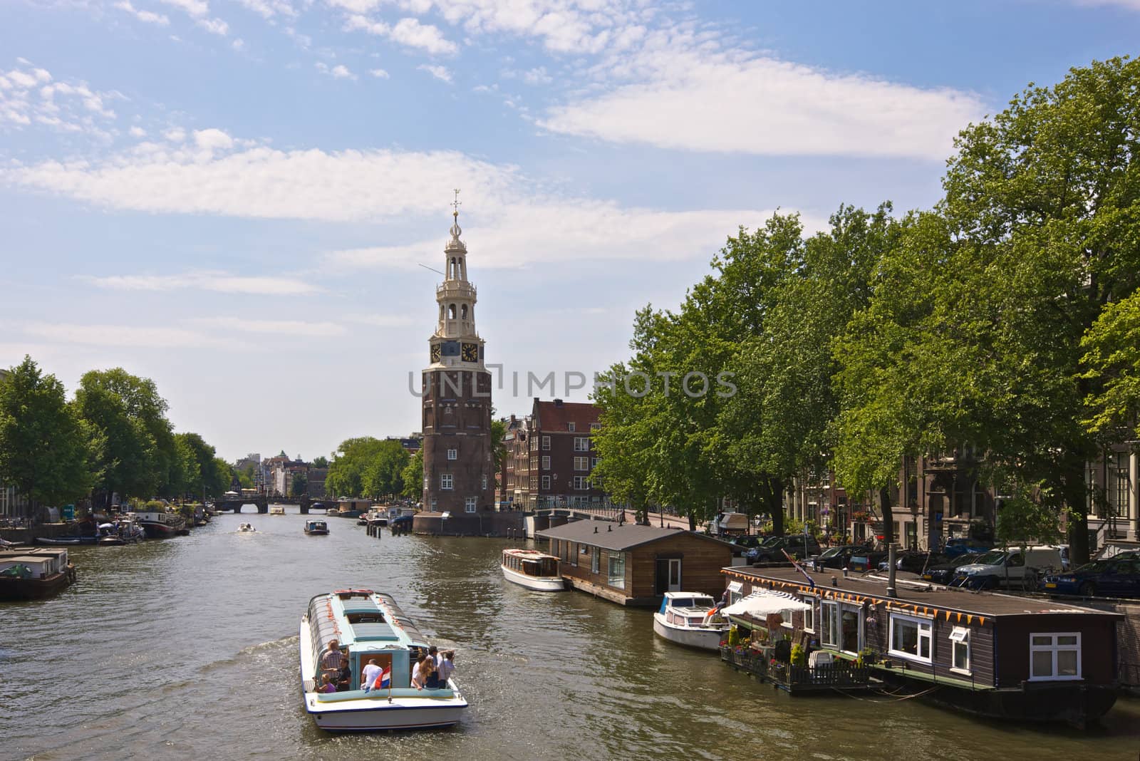 Amsterdam, Netherlands, Montelbaan Tower and canal cruise boat by johanelzenga