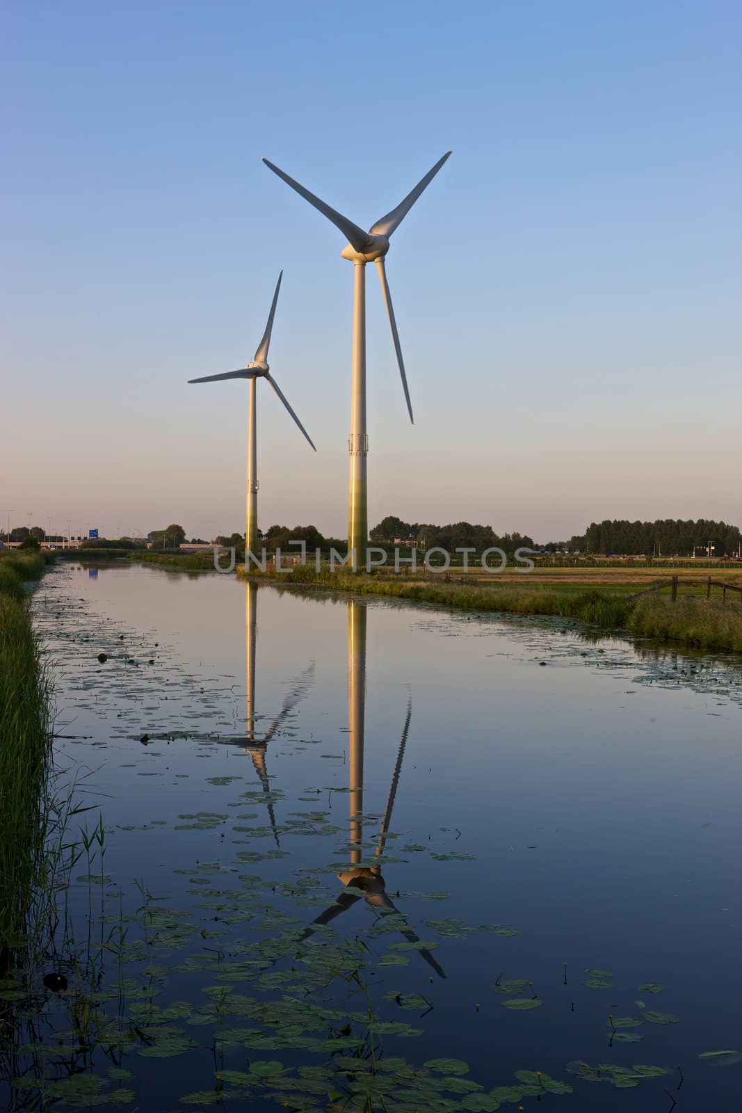 Two modern wind turbines in a Dutch landscape.