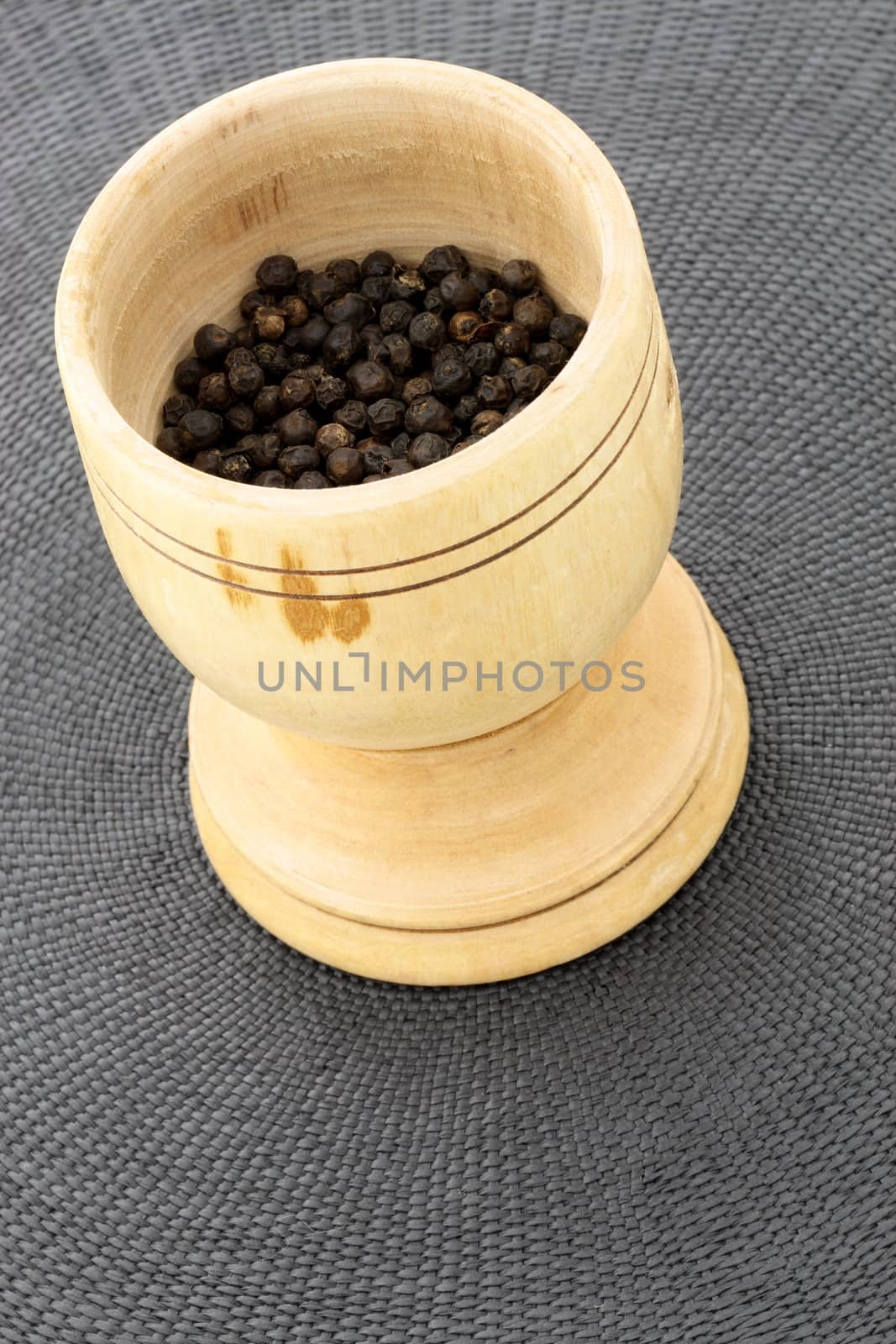 handmade wood mortar full with aromatic black peppercorns